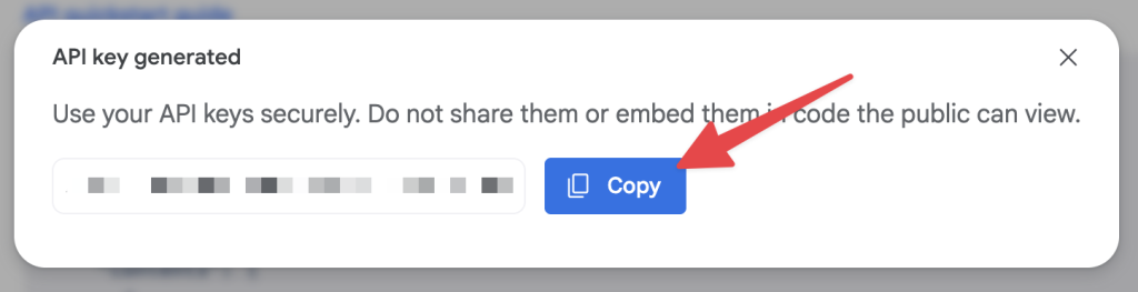 Google AI Studio modal showing a newly generated API key with a red arrow pointing to the “Copy” button.